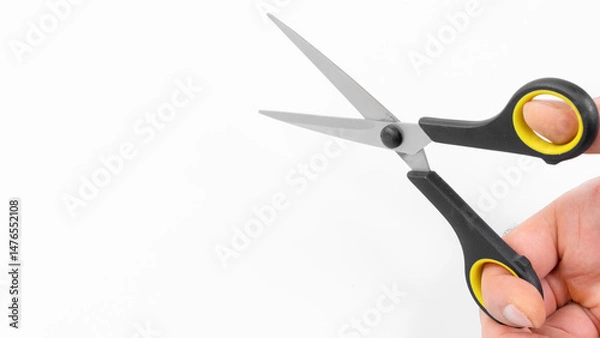 Fototapeta Close-up of a hand holding scissors ready for cutting tasks in a bright workspace environment