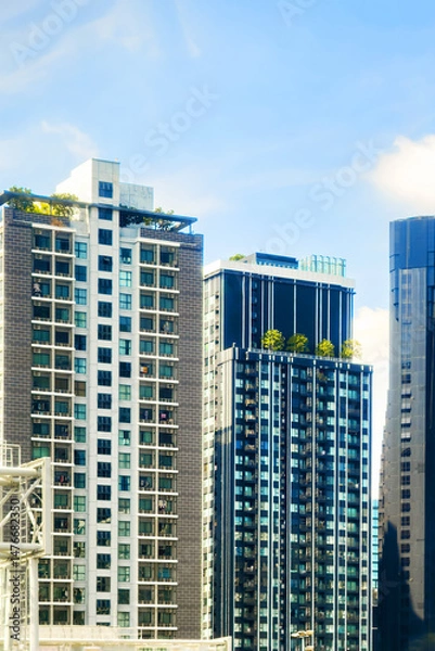 Obraz Modern skyscrapers with green terraces and blue sky, showcasing urban architecture and innovative design in a vibrant city environment
