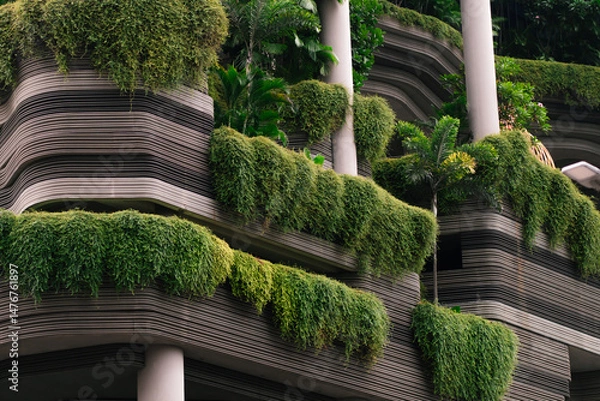 Fototapeta Modern architecture with layered horizontal lines and lush green vertical gardens cascading from the balconies.