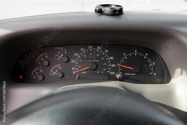 Obraz Dashboard cluster with analog gauges in a 2000s American pickup truck, showing speedometer, RPM, temperature, and fuel levels with steering wheel partially visible.