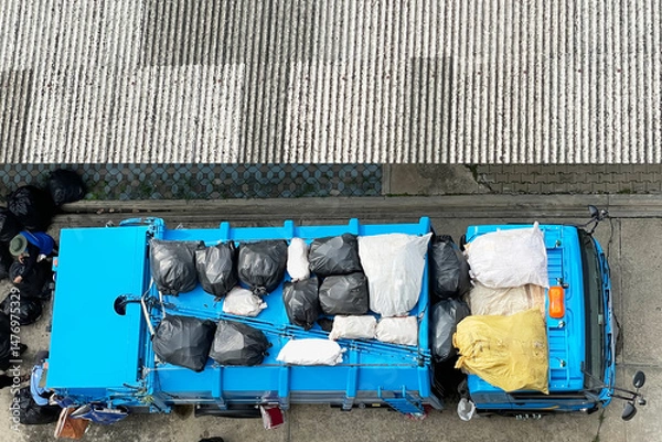 Fototapeta Aerial view show garbage collectors are loading garbage bags onto garbage truck. Image use for presentation background of managing the cleanliness of the city.
