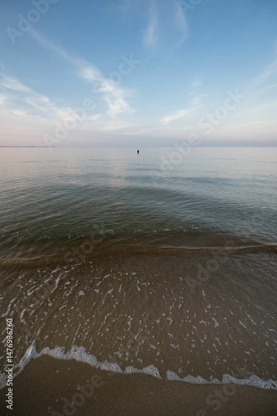 Obraz a person in a boat standing in the ocean water and shore line