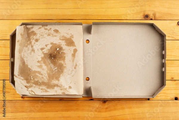 Obraz Pizza box with breadcrumbs on natural wooden table flat lay view