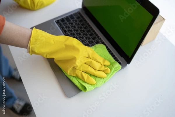 Fototapeta woman cleaning laptop with cloth, cleaning staff maid