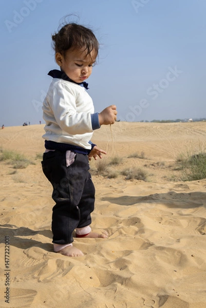 Fototapeta innocent child exploring desert sand with hand from flat perspective