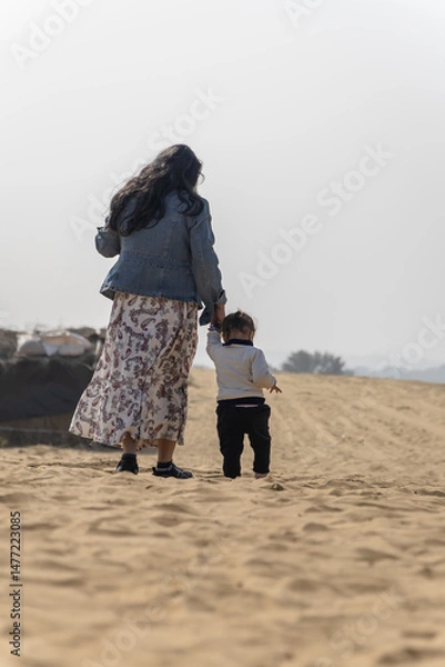 Fototapeta mother holding kid hand walking in desert at day from back