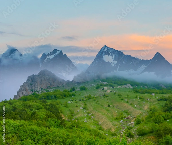 Fototapeta green mountain chain in dense mist and clouds
