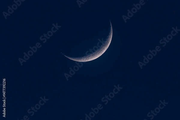 Fototapeta Detailed view of the crescent moon against a deep blue night sky, showing craters and surface texture in stunning clarity.