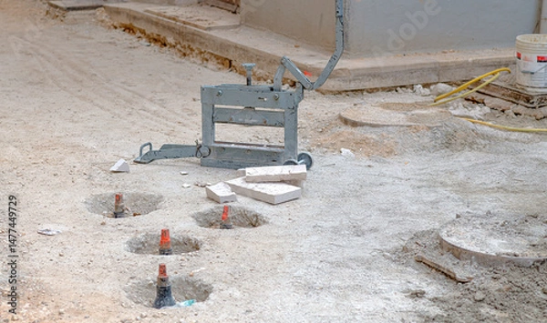Fototapeta Featured prominently is a durable block splitter machine, scattered debris and precisely bored holes the equipment illustrate in preparing a site for new infrastructure or paving. Selective focus