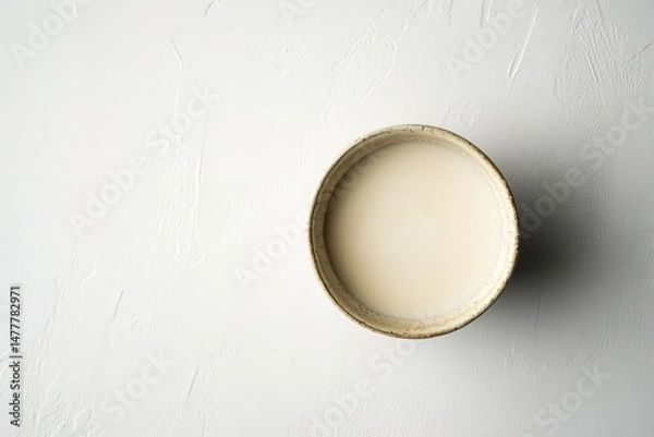 Fototapeta A small bowl of almond butter with a smooth texture, isolated on a plain white surface
