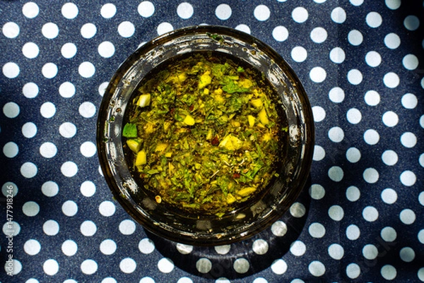 Obraz Chimichurri sauce in a glass bowl on a polka dot table 