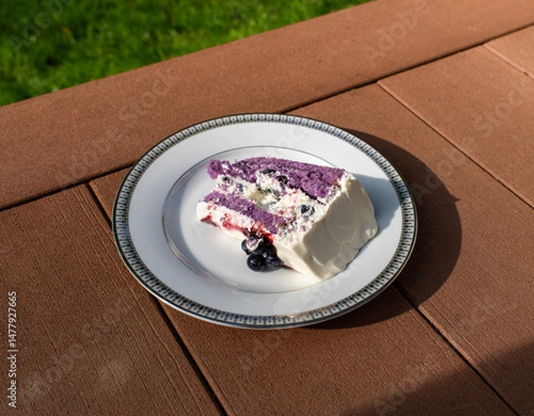 Obraz A slice of blueberry cake on a white plate on a wooden surface 