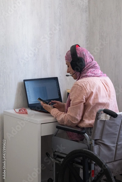 Fototapeta woman in muslim headscarf office style, working from home, disabled girl in wheelchair work from home, including disabled people