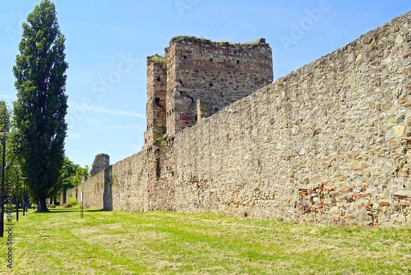 Fototapeta Impressive medieval fortifications of Europe: view from the courtyard of the defensive walls, a stone square tower and a ruined object in the background in the fortified suburb of Smederevo fortress.