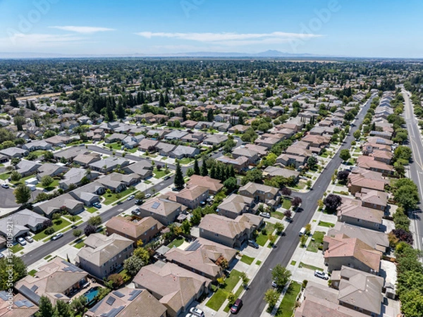 Obraz Aerial view of a suburban residential neighborhood in Stockton, California, showcasing rows of single-family homes, streets, and surrounding farmland. Ideal for topics related to urban planning, Calif