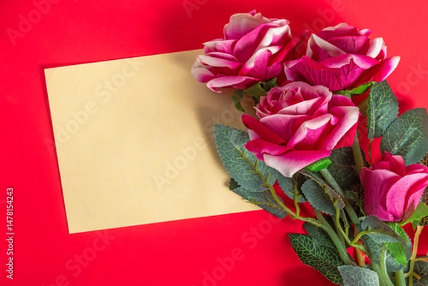 Fototapeta Beautiful pink roses with a blank card on a red surface.