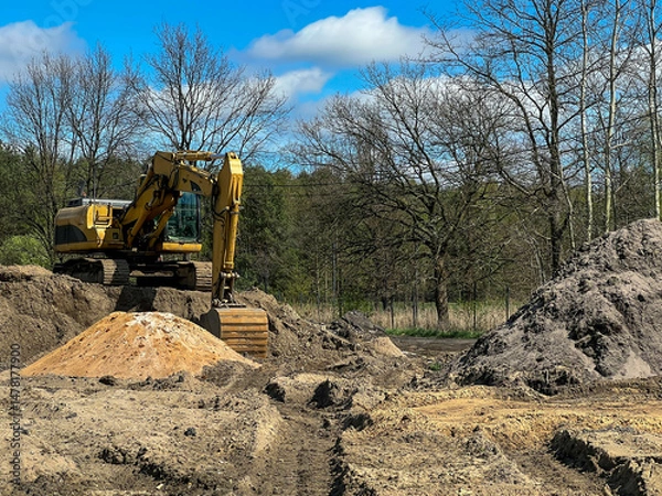 Obraz A large backhoe loader standing on a pile of earth