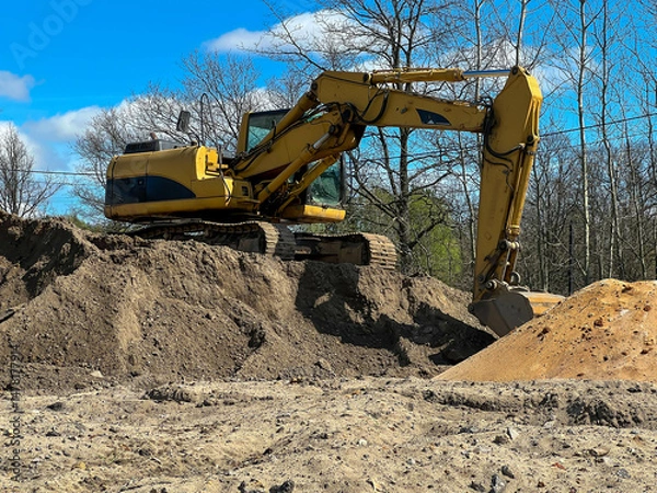 Obraz A large backhoe loader standing on a pile of earth