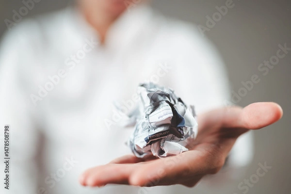 Fototapeta A businessman in a white suit crumples a piece of paper and holds it out in front of him.