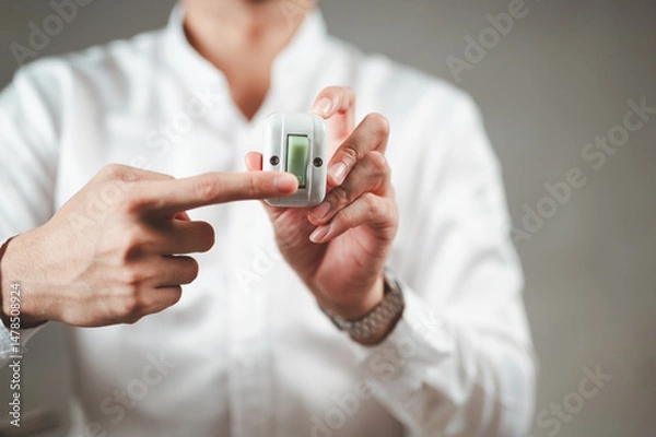 Fototapeta A businessman in a white shirt is pressing a light switch on his hand.