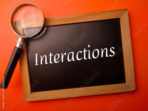 Fototapeta Wooden board with the word Interactions on a orange background