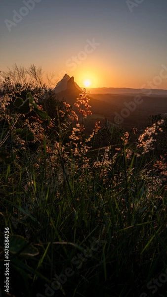 Obraz Sunset glow over wild grass and volcanic peaks in Queensland, Australia