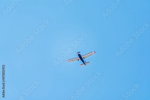 Fototapeta Small ultralight airplane with overhead wing and single propeller flying in sunset sky.