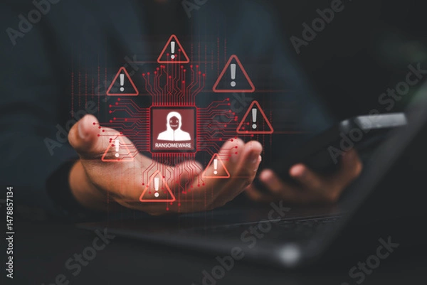 Fototapeta Malware attack virus alert. Ransomware malware attack and data breach. Man use smartphone and laptop with virtual warning sign with ransomware word. Warning notification, Cyber threats.