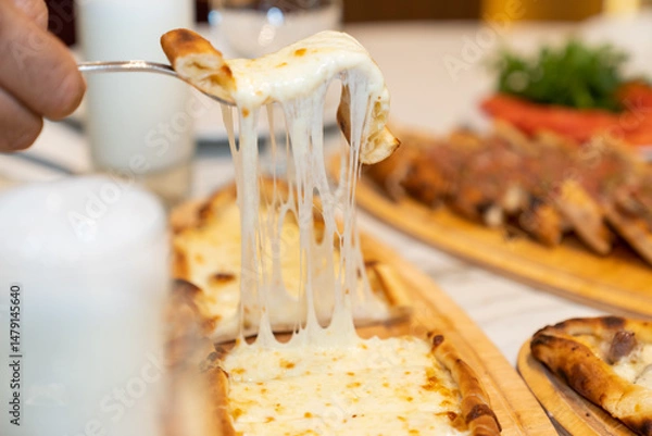 Fototapeta Close up view of eating sliced Turkish pizza with cheese served on a restaurant table.