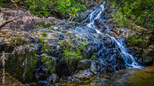 Fototapeta Tropical Waterfall Cascading Over Rocks in Lush Green Forest