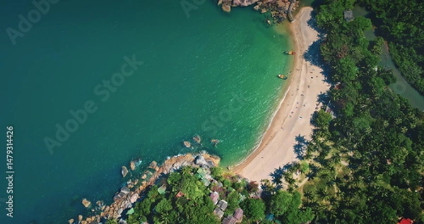 Fototapeta Aerial view capturing a tropical paradise with crystal-clear turquoise waters lapping against a pristine sandy beach, surrounded by lush vegetation and traditional huts