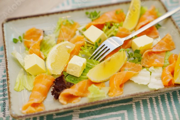 Obraz A plate with pieces of butter, red lightly salted fish and lemon for sandwiches.