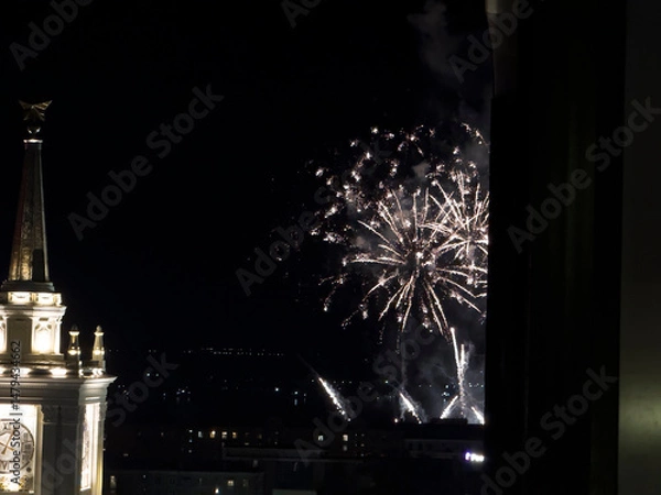 Obraz Fireworks illuminate the dark sky, creating a breathtaking display above city buildings during a nighttime celebration, captivating spectators.