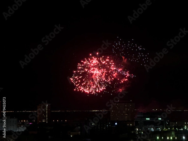 Obraz Fireworks illuminate the dark sky, creating a breathtaking display above city buildings during a nighttime celebration, captivating spectators.