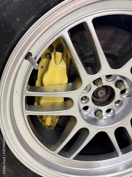 Fototapeta Detailed look at a yellow brake caliper nestled within an alloy wheel, highlighting automotive design features and performance enhancement.