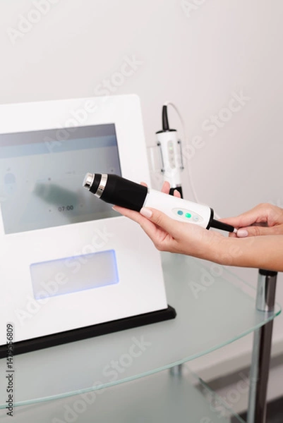 Fototapeta Woman hand holds a facial rejuvenation device with unique combination of advanced technologies, Tripollar RF, Oxygeneo and Ultrasound
