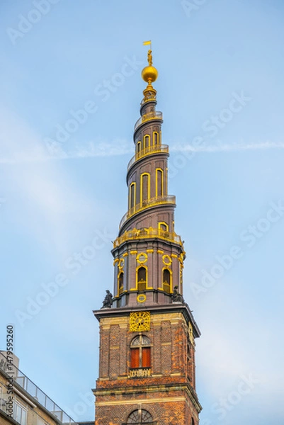Fototapeta The corkscrew spire of the Church of Our Saviour in Copenhagen rises prominently against a clear blue sky. Its intricate design showcases a blend of architecture and artistry.