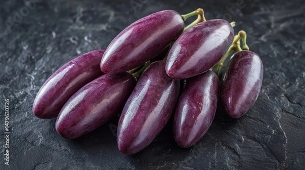Obraz A handful of elongated Moon Drop grapes resting on a dark slate surface, emphasizing their unique shape