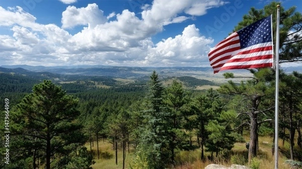 Fototapeta American Flag Gently Waving in the Wind on a Hill Surrounded by Lush Green Trees and Vibrant Blue Sky