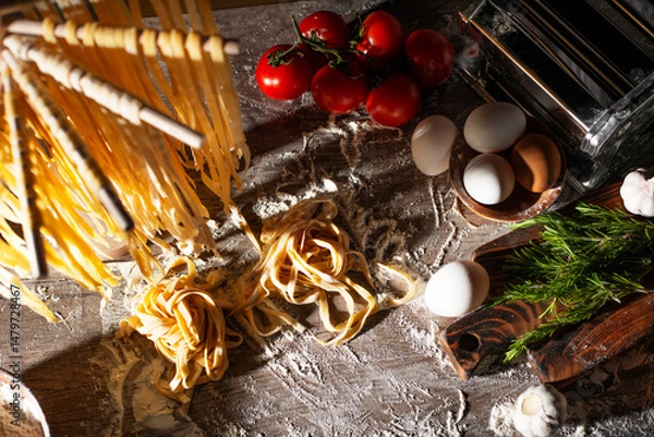 Obraz Homemade noodles hanging on wooden dryer rack over messy kitchen table background high angle top view