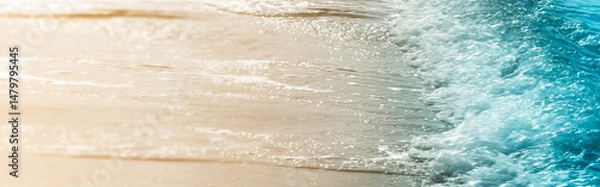 Obraz closeup of a real blue water wave at sand beach in glittering sunlight, summer nature idyll, blurred background banner concept with copy space for vacation, travel and relaxation outdoors