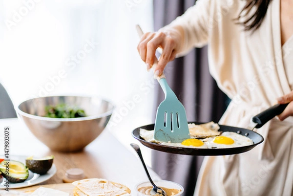 Obraz Close-up of hand flipping fried eggs in pan
