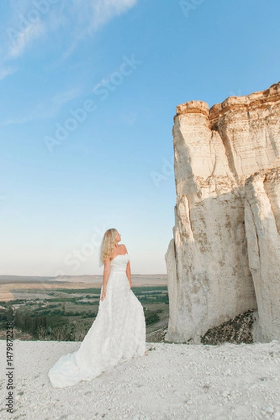 Obraz a woman in a white dress, a bride on a mountain with a blue sky. Beautiful nature, freedom, enjoyment of life. High quality photo
