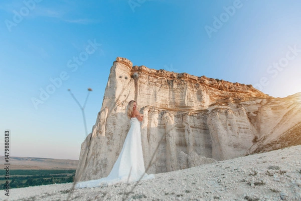 Obraz a woman in a white dress, a bride on a mountain with a blue sky. Beautiful nature, freedom, enjoyment of life. High quality photo