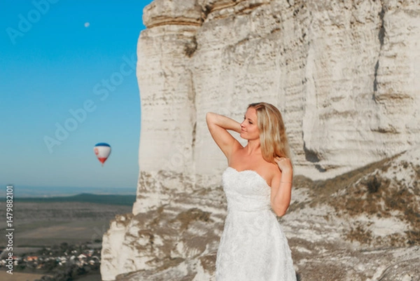 Obraz a woman in a white dress, a bride on a mountain with a blue sky. Beautiful nature, freedom, enjoyment of life. High quality photo