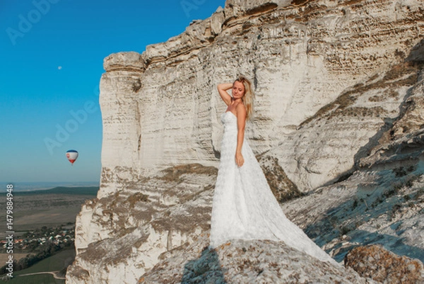 Obraz a woman in a white dress, a bride on a mountain with a blue sky. Beautiful nature, freedom, enjoyment of life. High quality photo