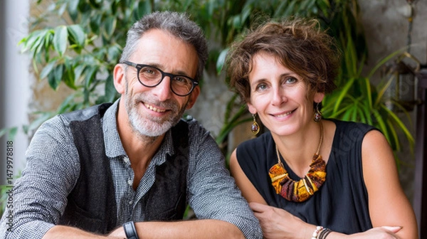 Fototapeta Mature couple sharing warm smile while sitting at cafe, surrounded by verdant greenery, reflecting contentment and deep emotional bond