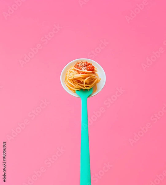 Fototapeta Concept of Italian food with delicious paste, spaghetti with tomato souse on turquoise green fork on pink background.
