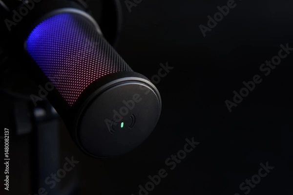 Fototapeta Close-up of a black RGB condenser microphone glowing with blue and red light, perfect for illustrating podcasting or streaming equipment. Photo