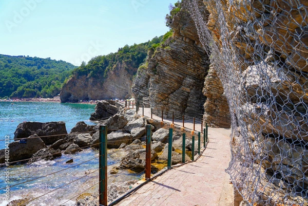 Fototapeta Waterside pathway to Mogren Beach nestled under a cliff on the Budva Riviera along the coast of the Adriatic Sea in Montenegro